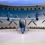 Protótipo de veículo elétrico futurista com hélices exposto em ambiente interno.