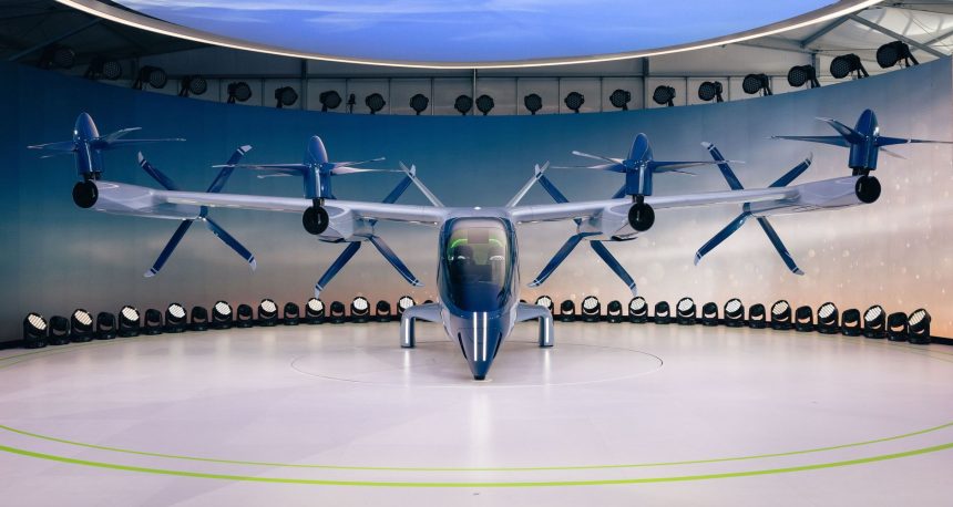 Protótipo de veículo elétrico futurista com hélices exposto em ambiente interno.